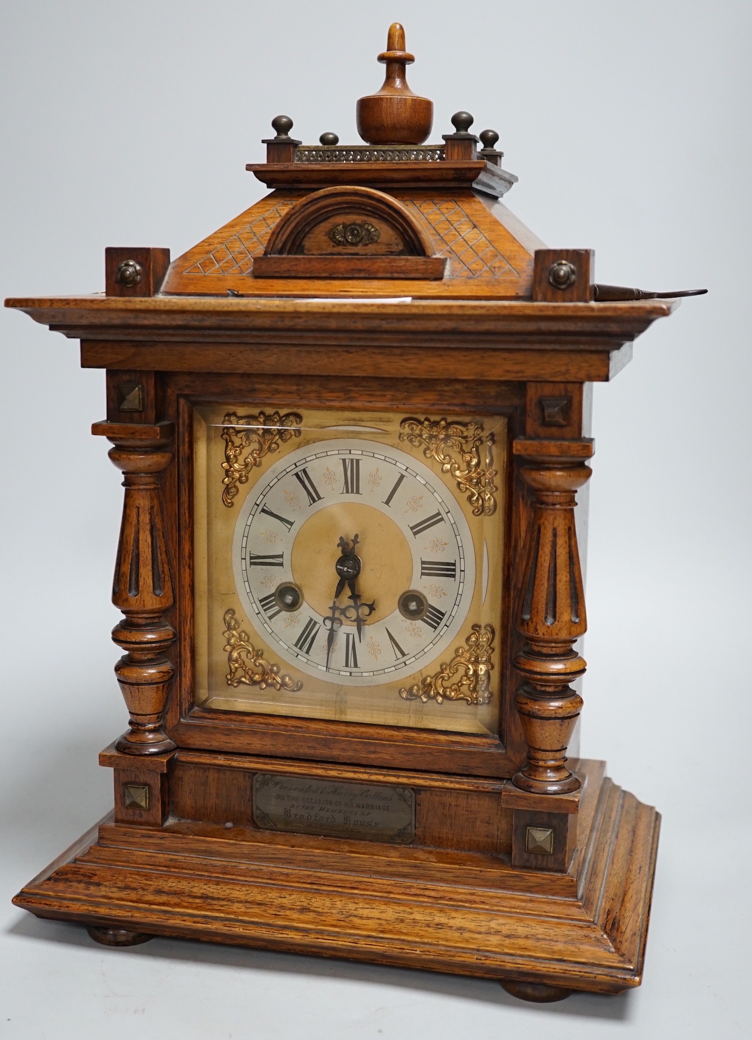 A German oak cased clock, plaque reads ‘Presented to Harry Collins on the occasion of his marriage by the members of Bradford House May 1st 1897’. Height 40cm